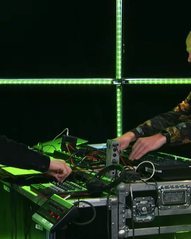Tinlicker performing live inside a green light cube