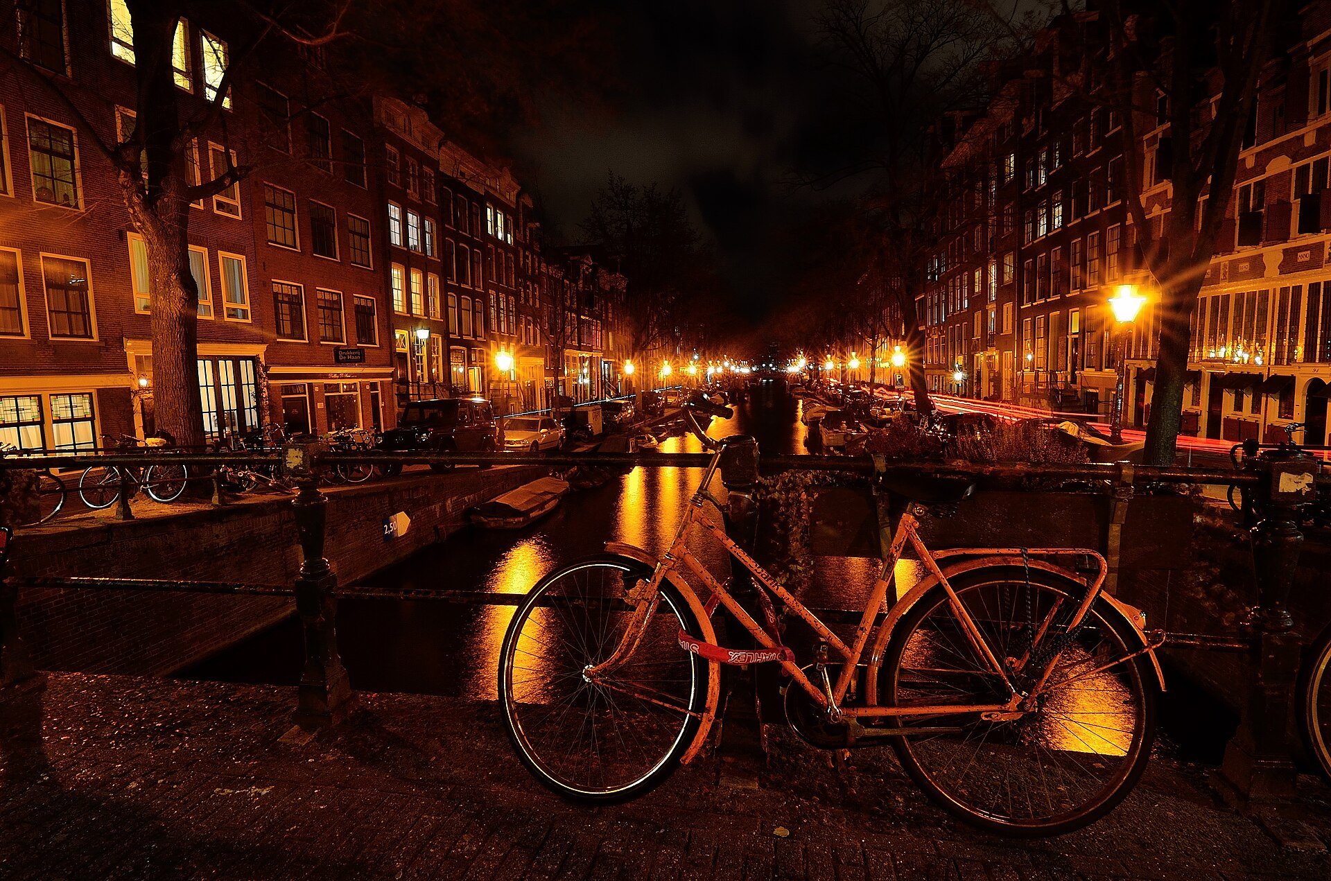A bicycle against a canal railing in Amsterdam at night