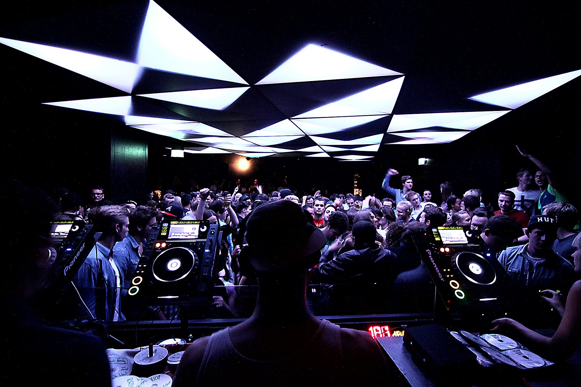 View from the DJ booth over a dancing crowd in a techno club