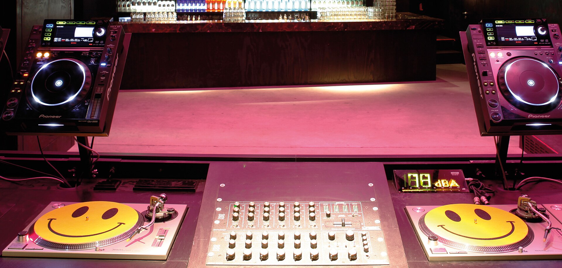 A techno-club DJ booth with two CDJs, a mixer and two turntables