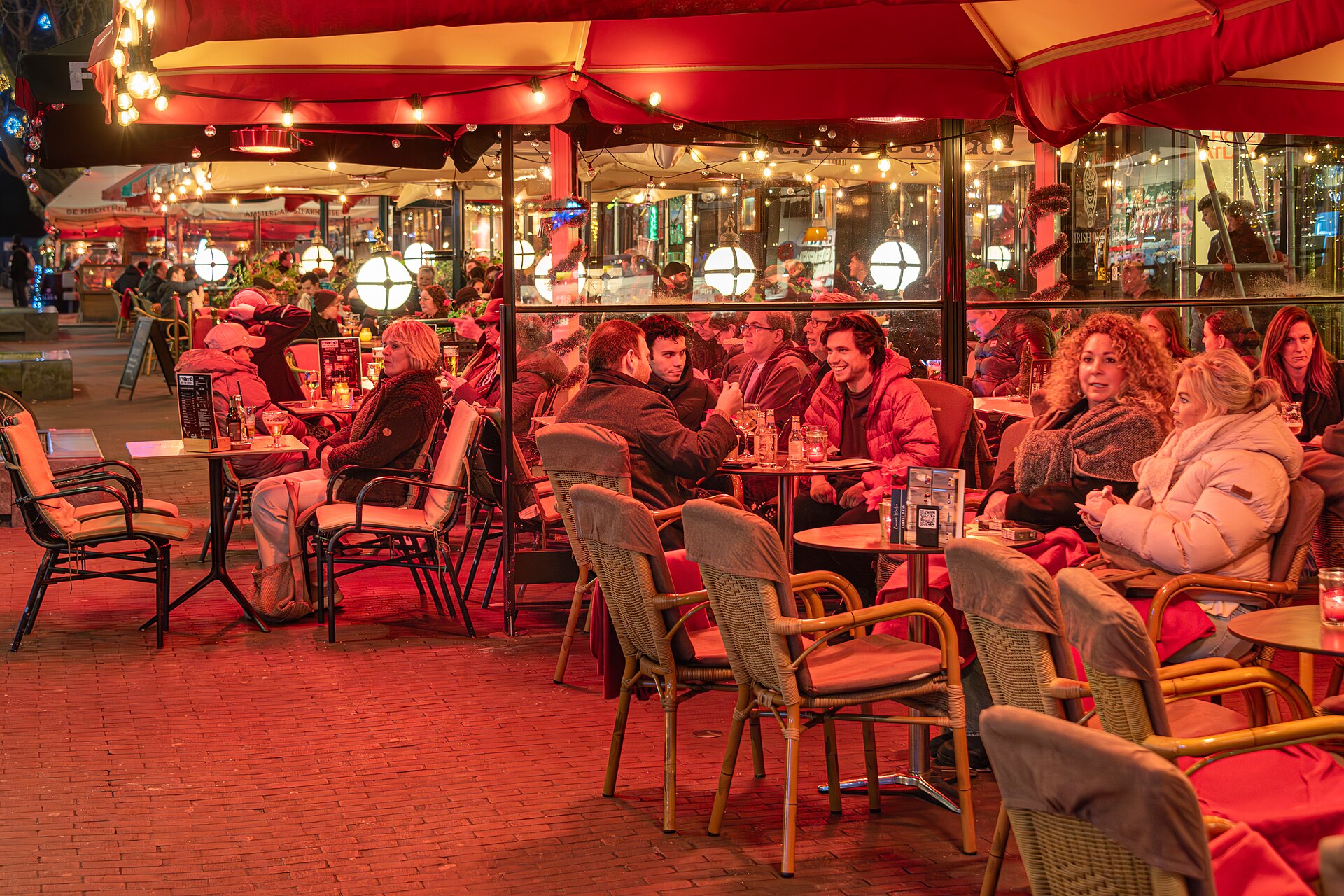 Red-lit café terraces on Rembrandtplein in the evening